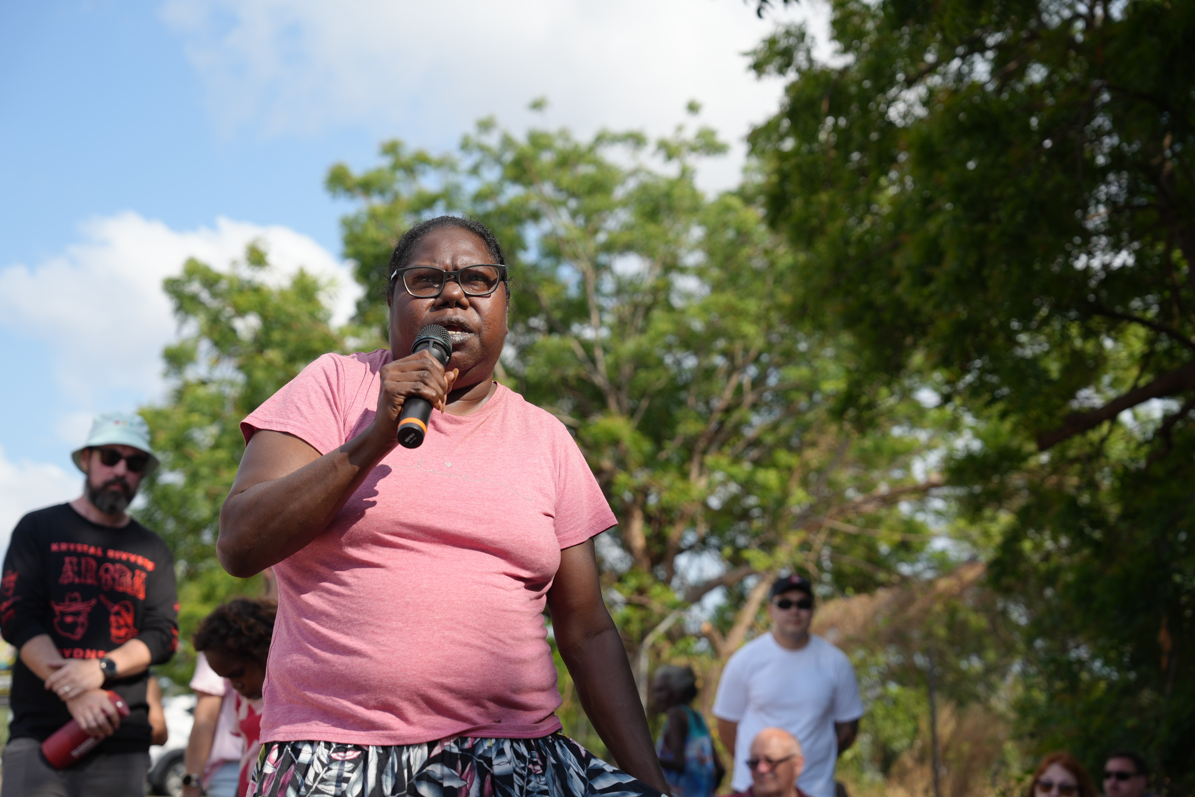 Janelle Guyirkuyir speaks into a microphone wearing a pink t-shirt.