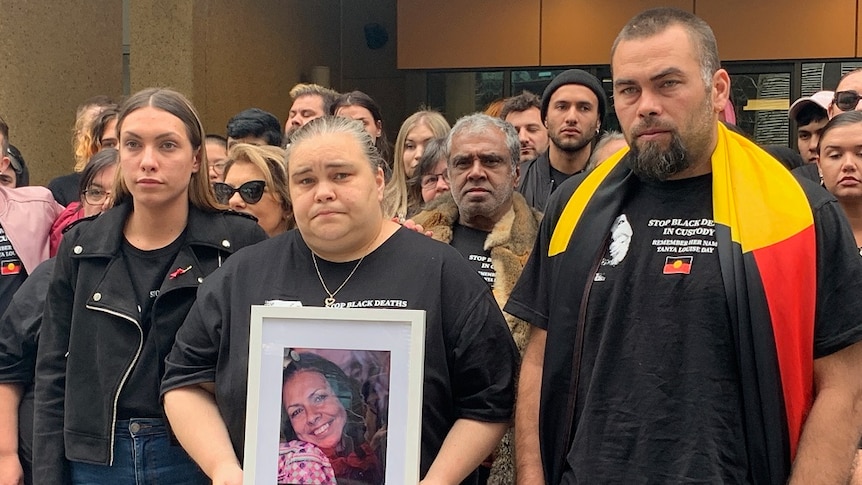 Tanya Day's children hold up a picture of their mother. Supporters stand behind the family.