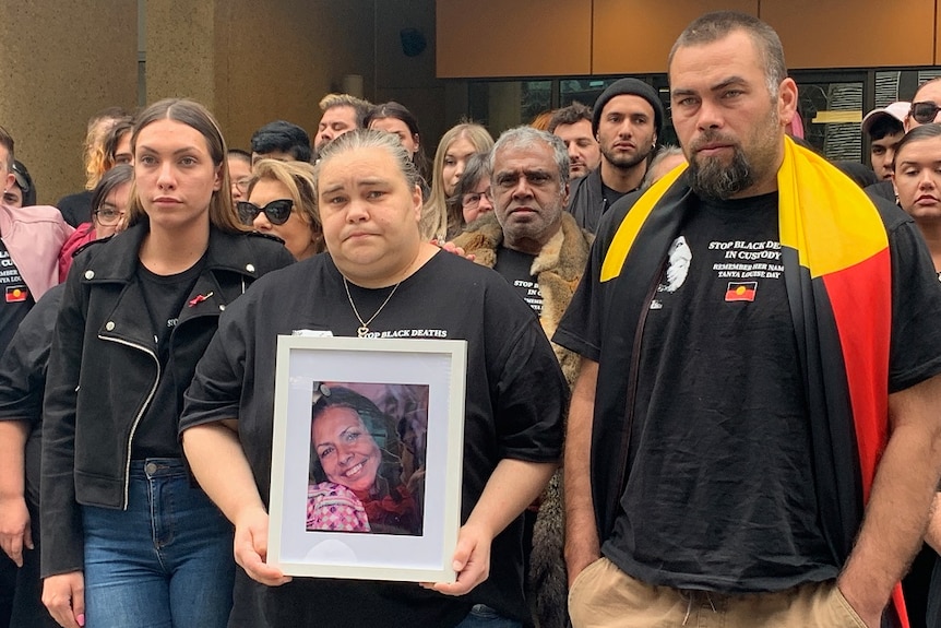 Tanya Day's children hold up a picture of their mother. Supporters stand behind the family.