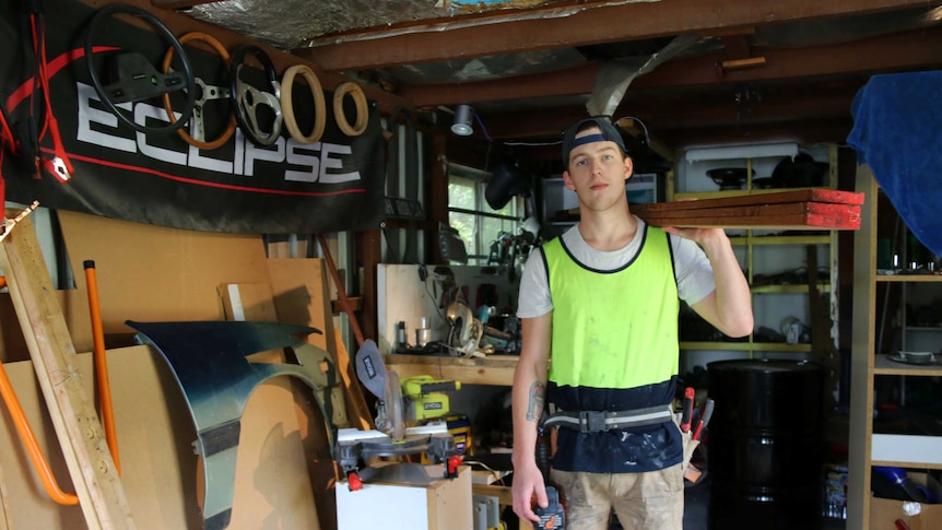 Callum White holding tools in his Belconnen shed