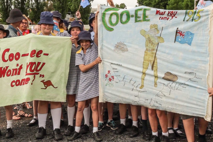 School students hold banners painted with co-ee 1915 and slogans