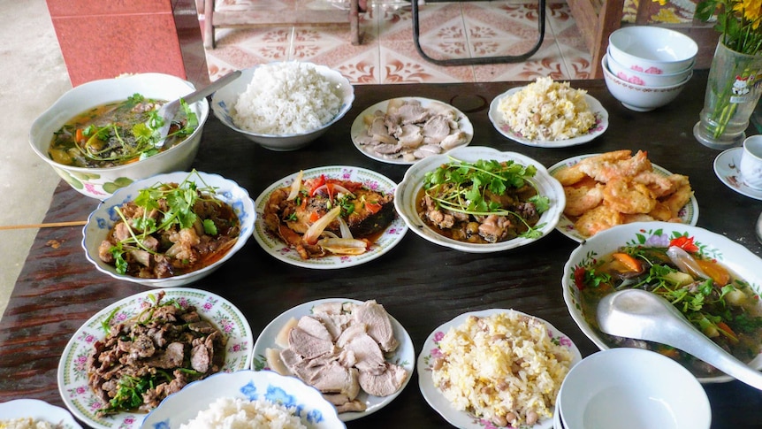 A table of Vietnamese dishes, including rice, meat, soup and vegetables dishes.