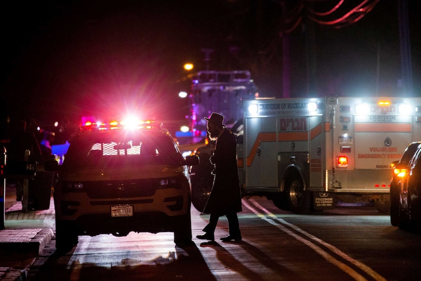 A police car with sirens illuminate the night and a silhouette of a Jewish man