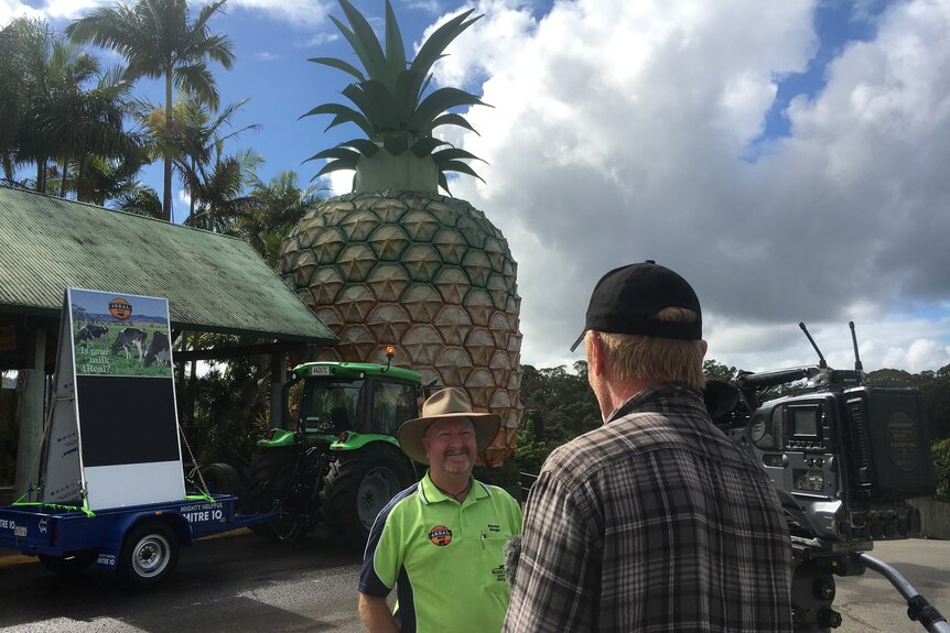 Greg Dennis being interviewed by a cameraman outside the Big Pineapple on the Sunshine Coast.