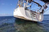 A low shot showing the back of a yacht stranded on a reef at sea.