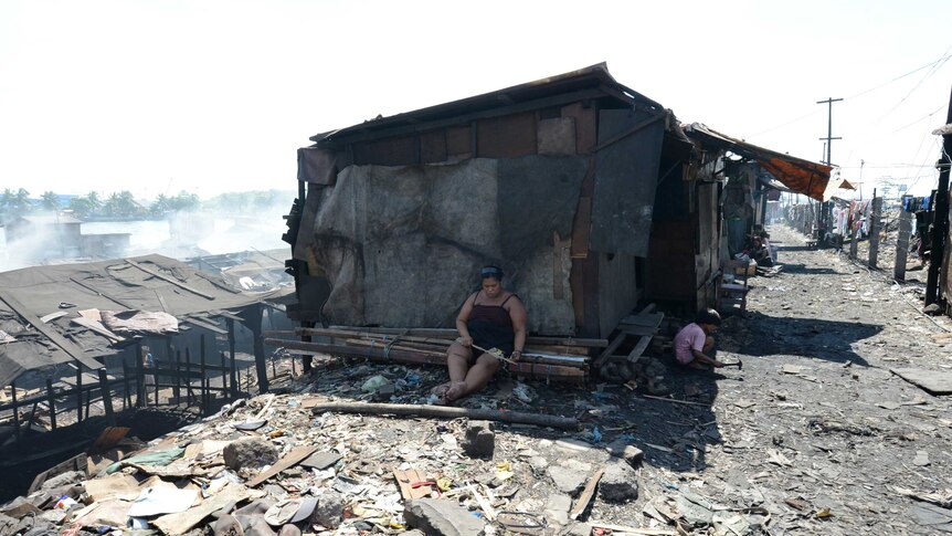 A woman sits near her makeshift house in the slums of Manila
