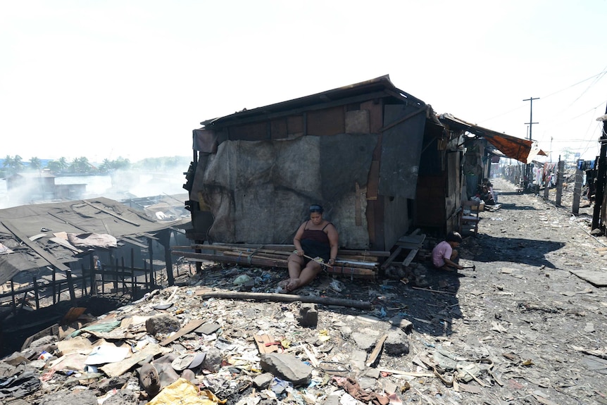 A woman sits near her makeshift house in the slums of Manila