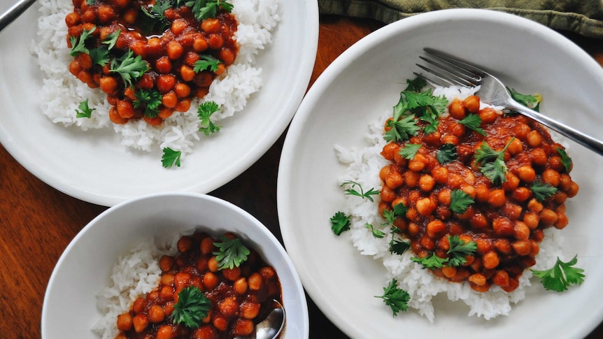 Three bowls of tomato chickpeas served over rice and topped with parsley, a healthy and warming family dinner.