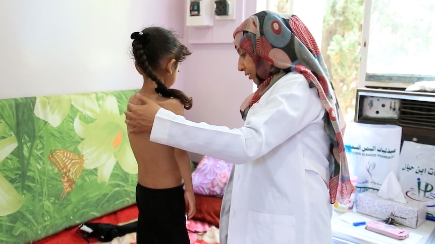 A doctor in a hijab treats a child in a hospital room.