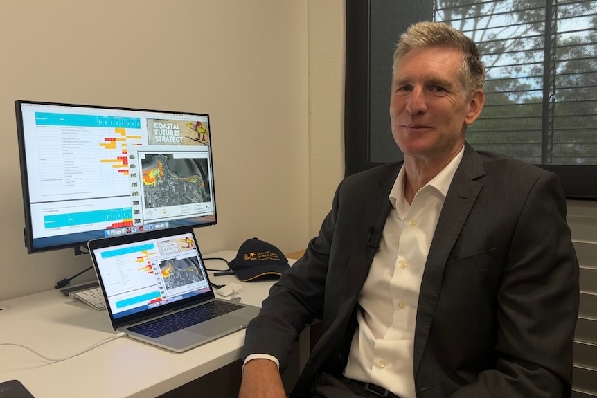 Middle aged man sitting in office next to his laptop 