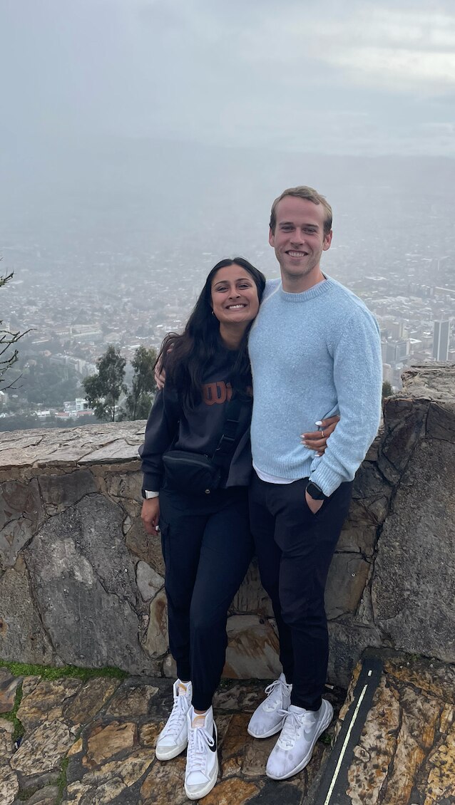 A couple stands at a lookout and smiles