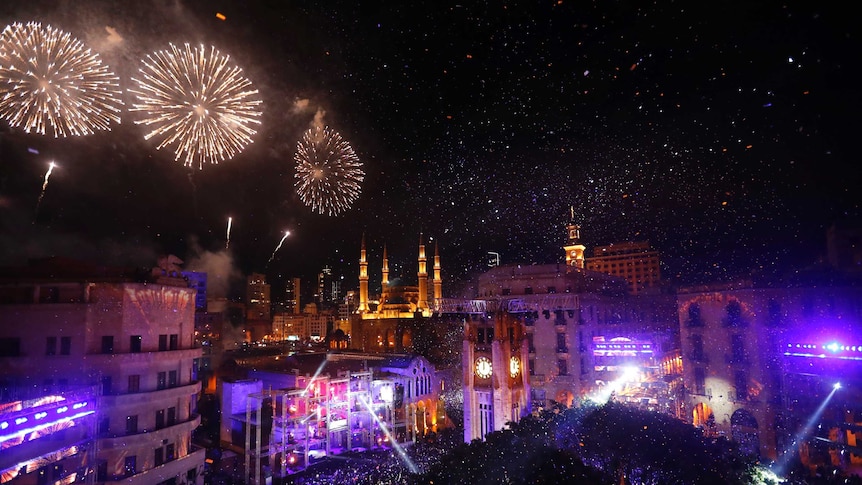 A large crowd watches fireworks explode over Beirut.