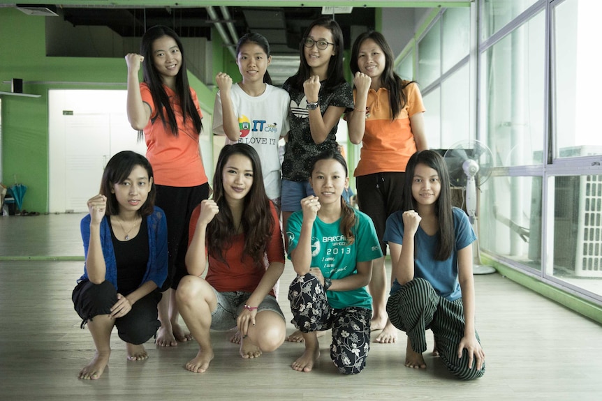 Michelle and a group of her students pose for a photo in a training hall.