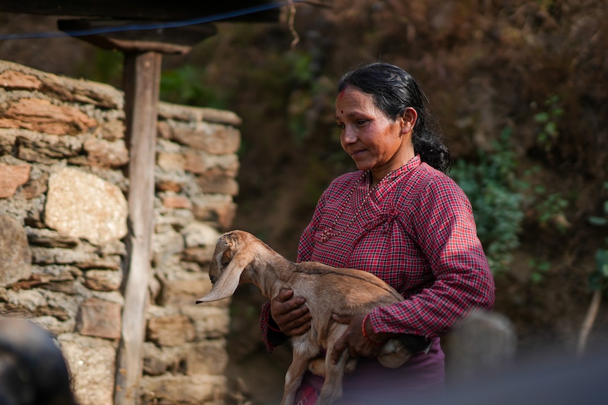 A woman holds a baby goat 