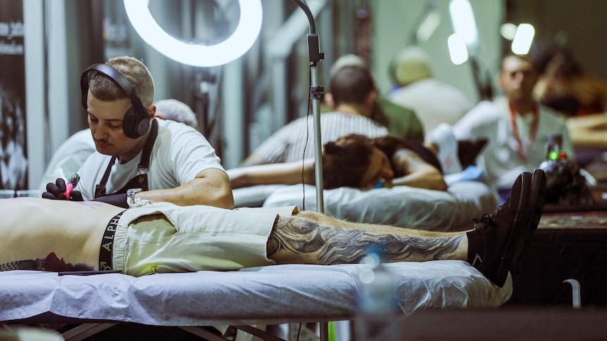 Two men tattooing at a tattoo expo held in Brisbane on July 12 2019