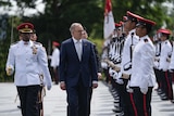 Anthony Albanese walks past an honour guard of Singapore armed forces personnel in white dress uniforms.