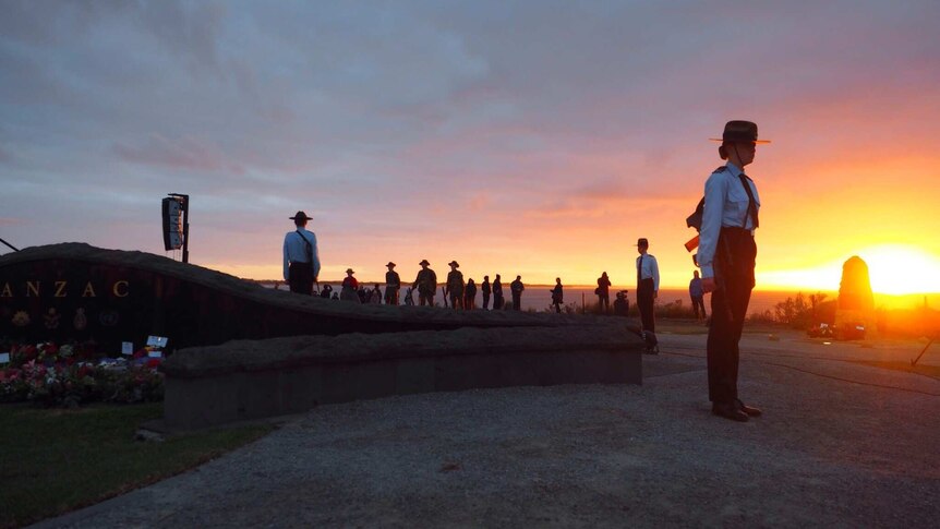 Soldiers stand in a circle around a memorial by the sea at the dawn service in Torquay, Victoria.