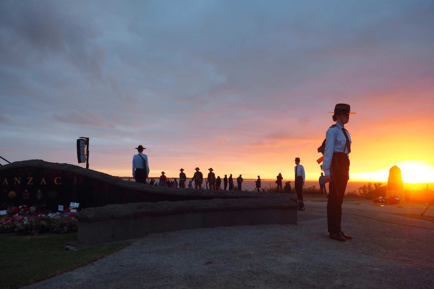 Soldiers stand in a circle around a memorial by the sea at the dawn service in Torquay, Victoria.