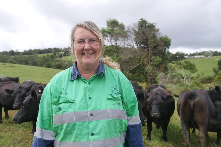 Cattle producer Mandy Tennent stands in a paddock, Australian lowline cattle are visible behind her
