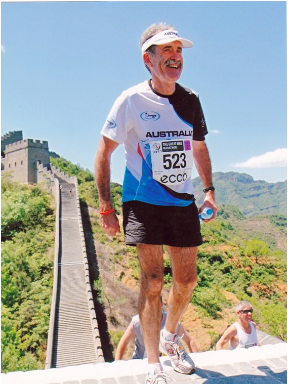 A runner stands on top of the Great Wall Marathon China under a clear sky.
