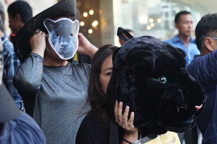 People wearing leopard masks in a crowd.