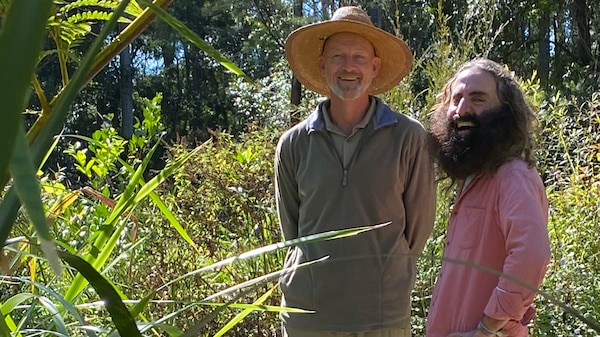 Two men standing in a native bushland garden