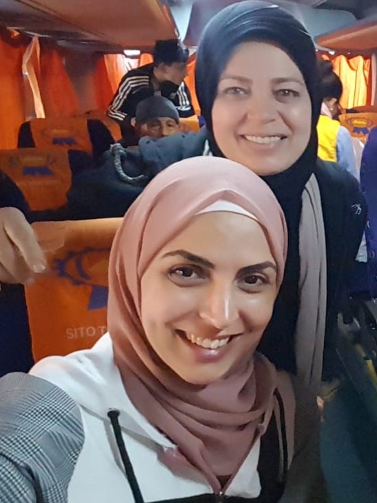 Two women wearing hijabs sitting in a bus. 