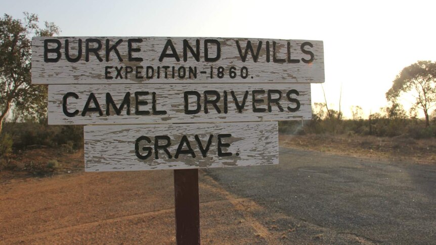 old sign on desert road that reads burke and wills, camel drivers, grave