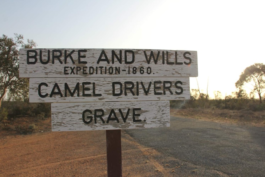 old sign on desert road that reads burke and wills, camel drivers, grave