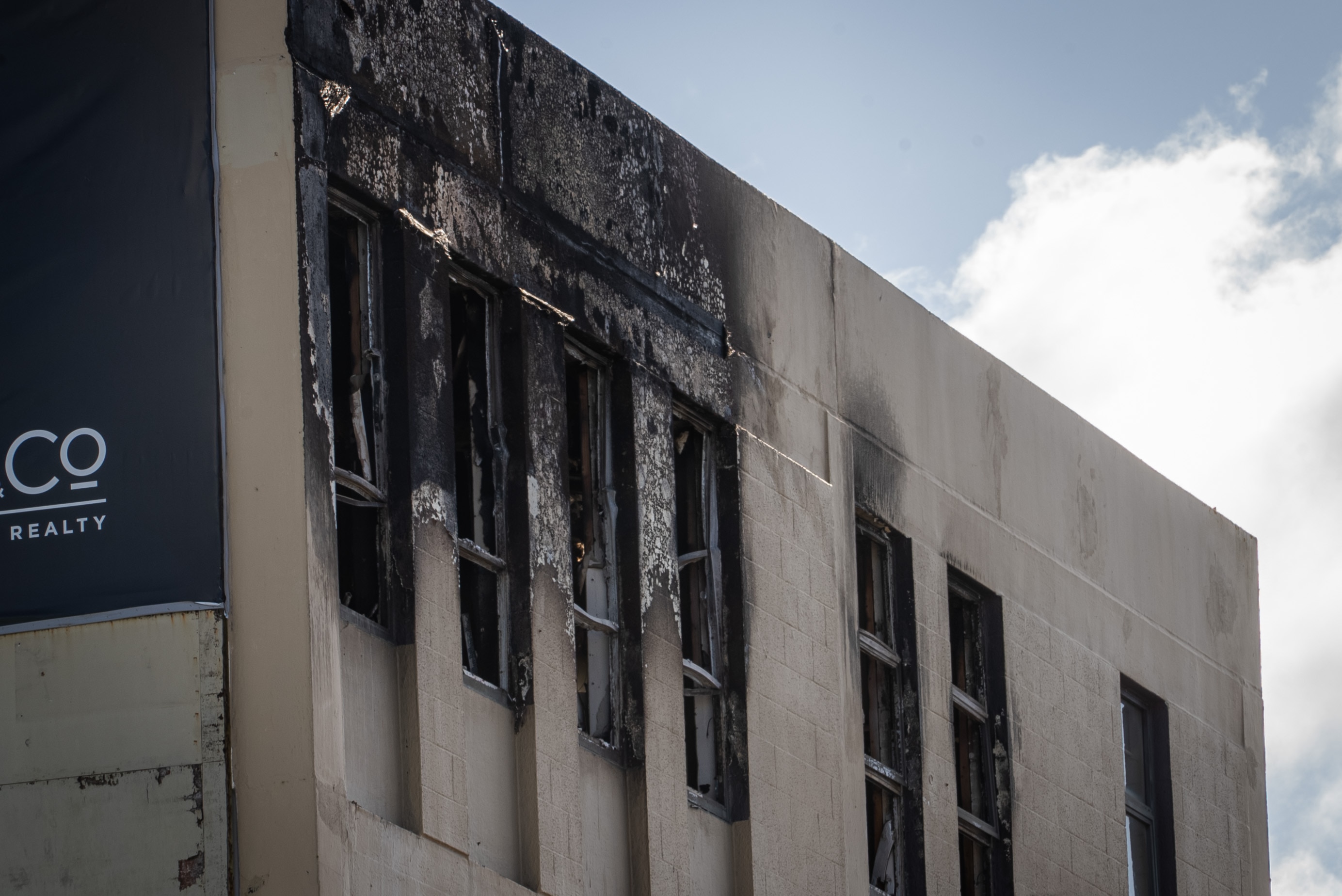 The top floor of a building shows fire damage to external walls and windows