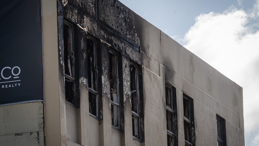 The top floor of a building shows fire damage to external walls and windows
