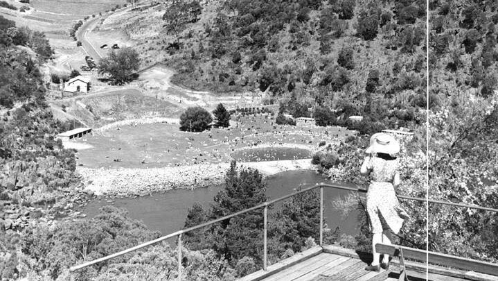 Black and white photo of a lady wearing hat looking down onto a pool and a river