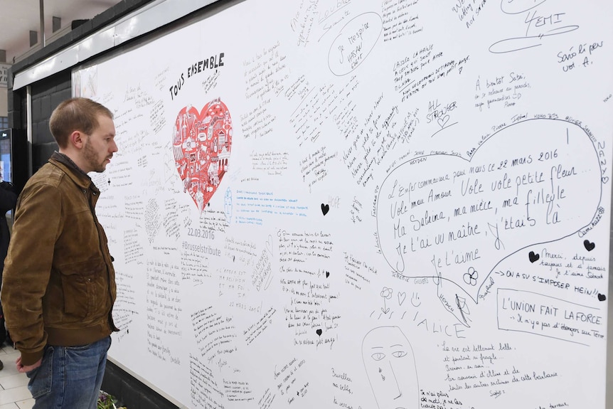 A man reads messages on a commemorative wall at the Maalbeek metro station.