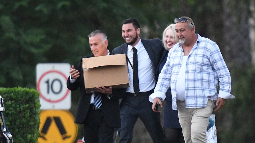 A smiling man in a suit accompanied by three people