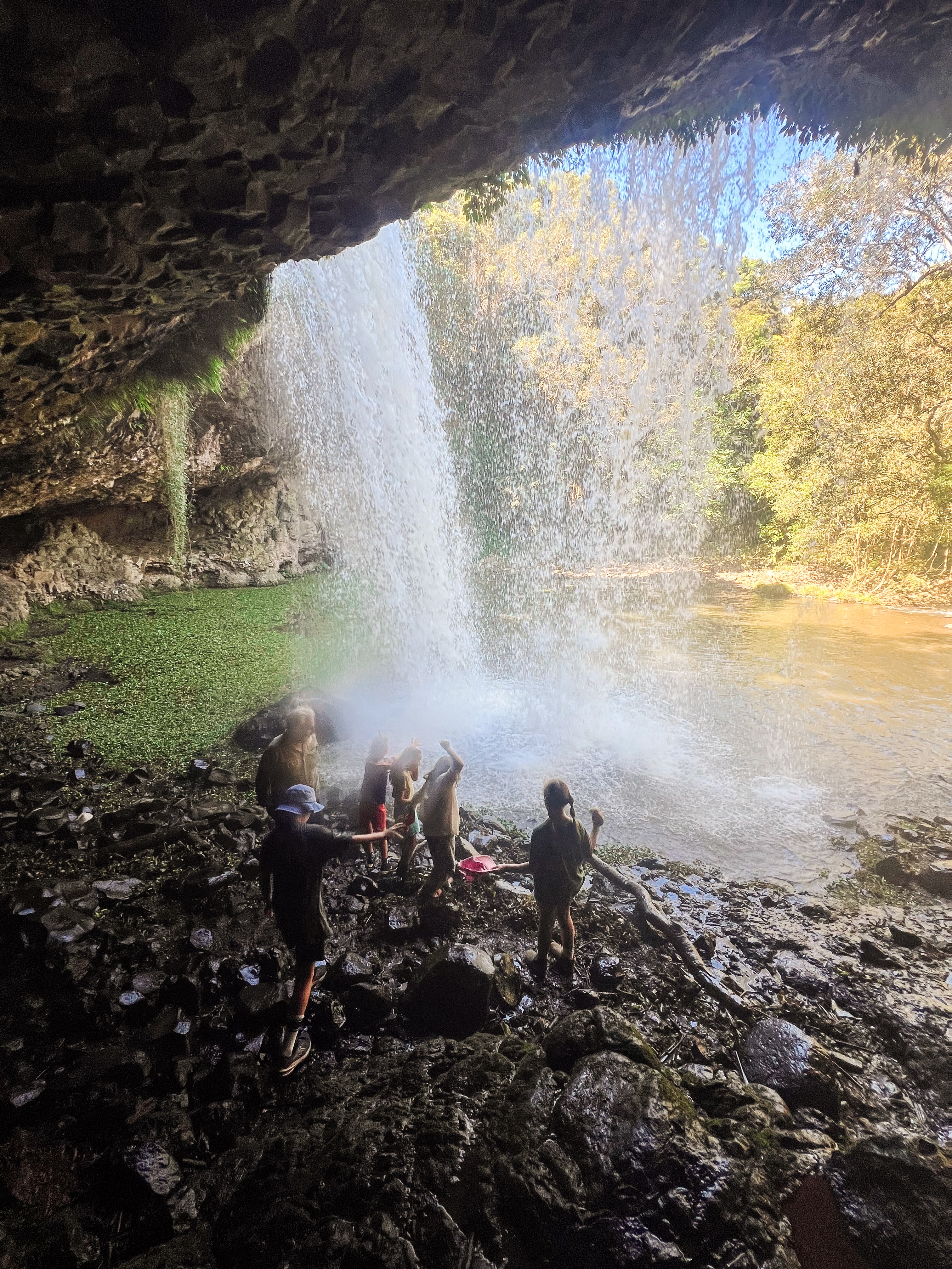 Los niños juegan bajo una cascada y se paran sobre las rocas.
