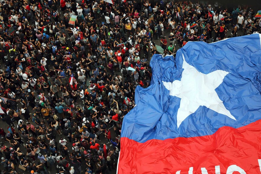 A bird's eye view of millions of protesters, carrying a huge, oversized Chilean flag
