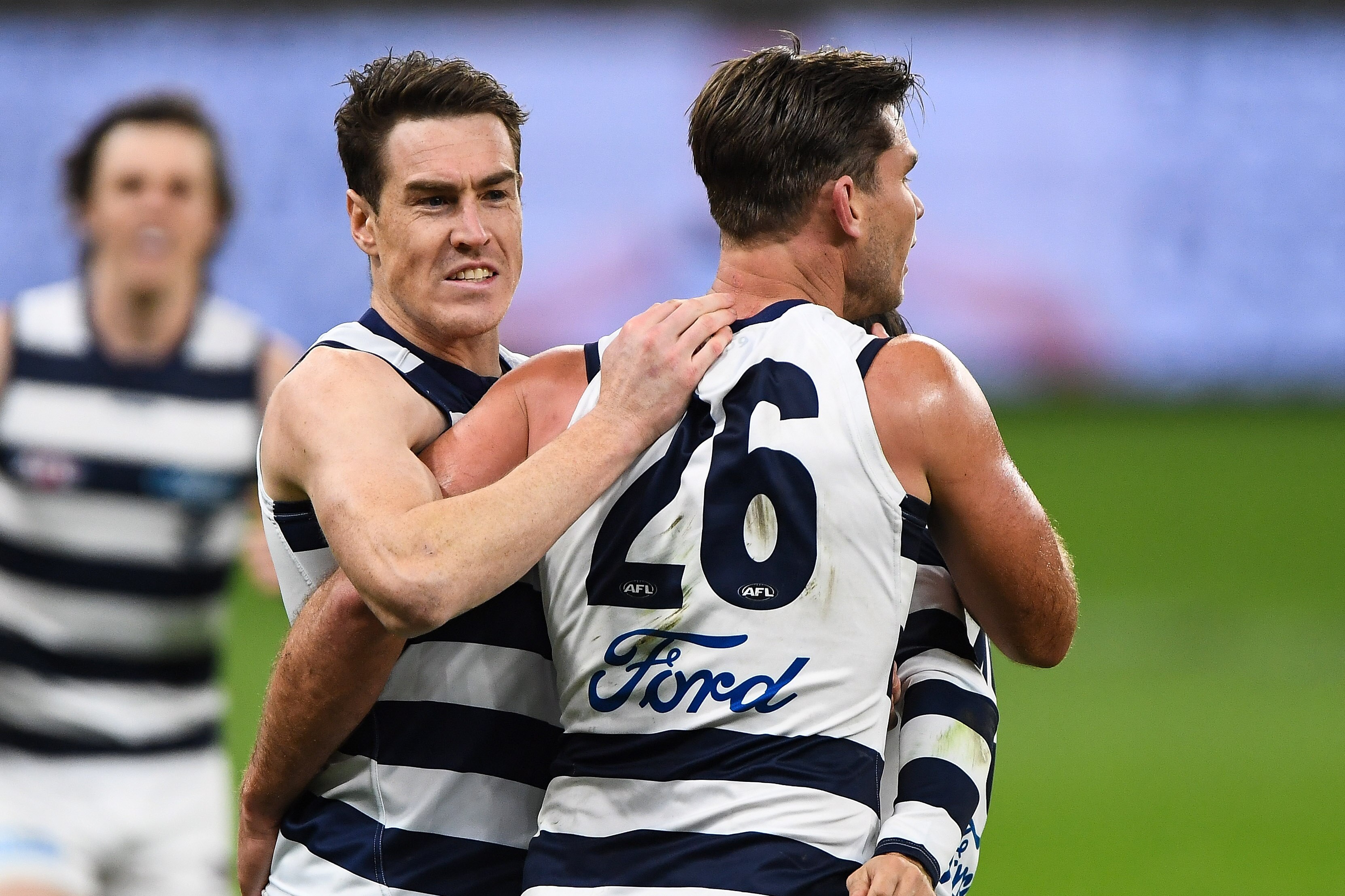 Two AFL teammates hug after a goal for their team. 