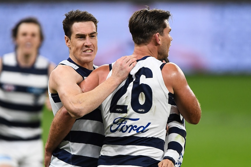 Two AFL teammates hug after a goal for their team. 