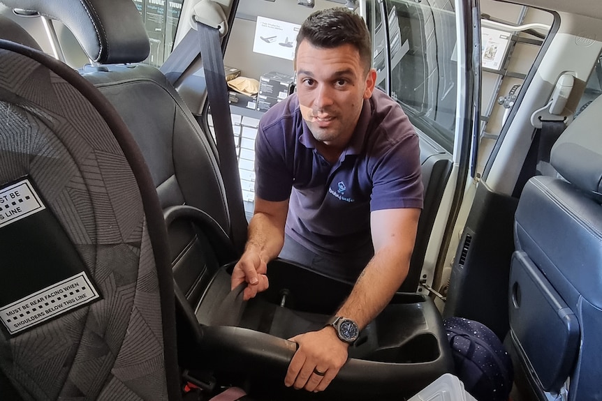 A man installs a car seat in a car.