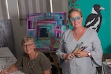 Two women in an art studio holding paint brushes