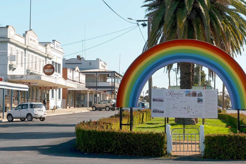 A rainbow sign in front of a town
