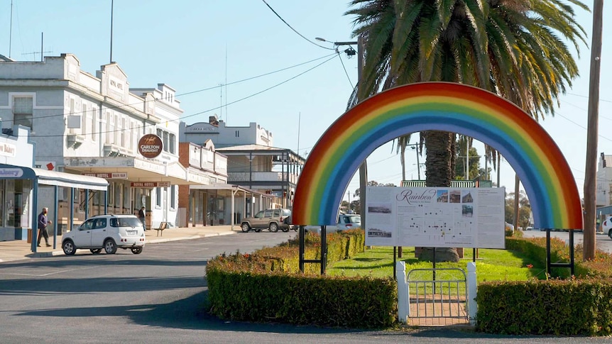 A rainbow sign welcomes people to a quiet bush township