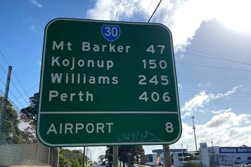 A sign on the side of a highway with distances to different destinations