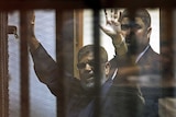 Deposed Egyptian President Mohamed Morsi waves to a crowd after being sentenced to death