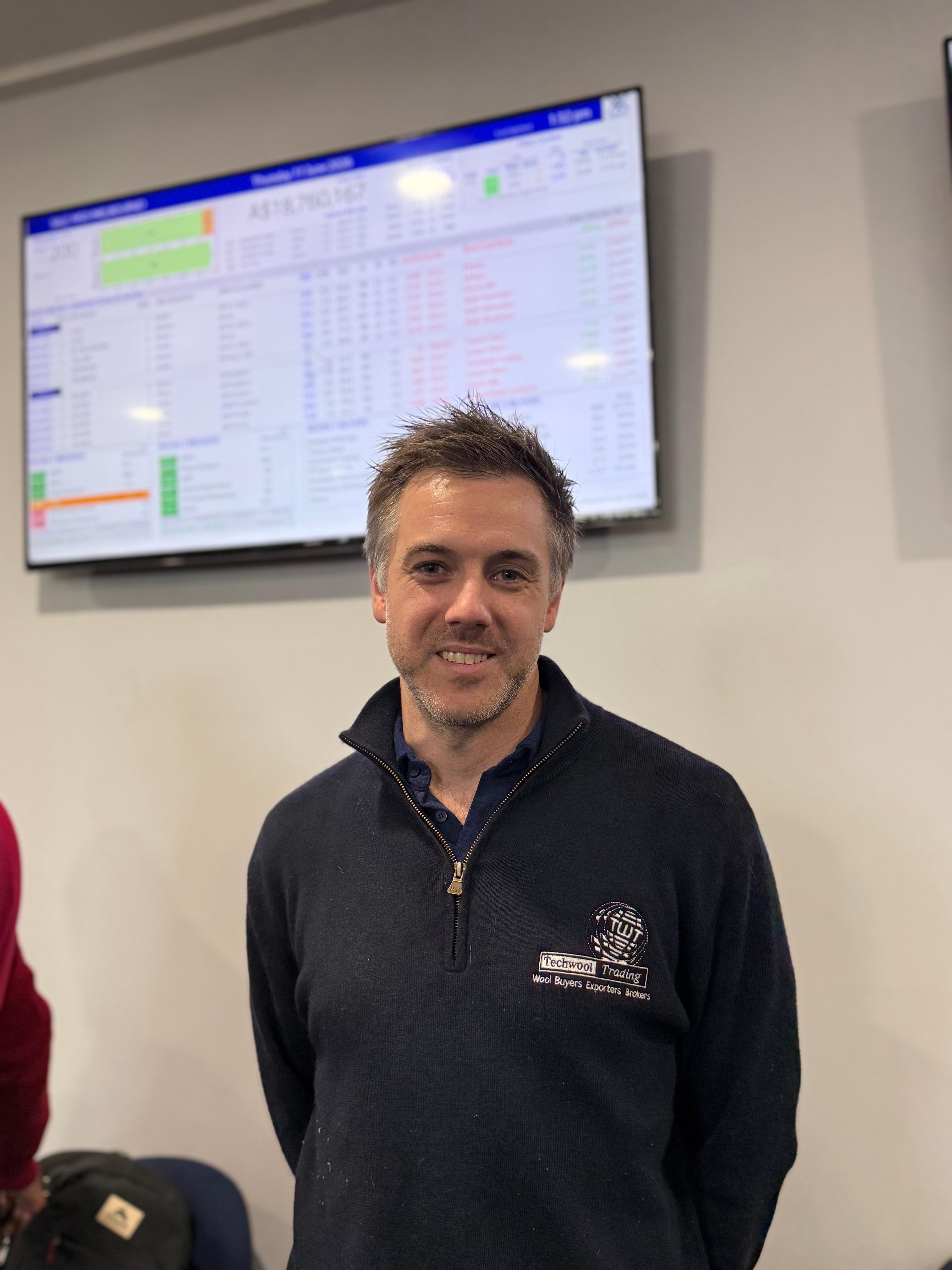 A man smiling in front of a trading screen
