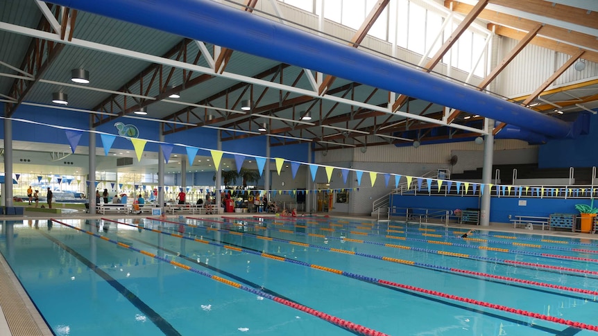 An Olympic sized swimming pool, with seperate lanes inside an indoor leisure centre.