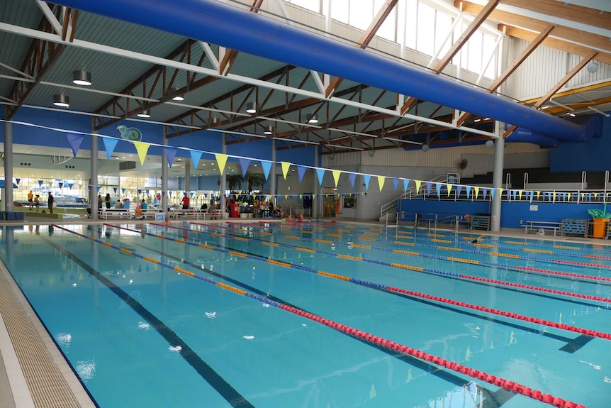 An Olympic sized swimming pool, with seperate lanes inside an indoor leisure centre.
