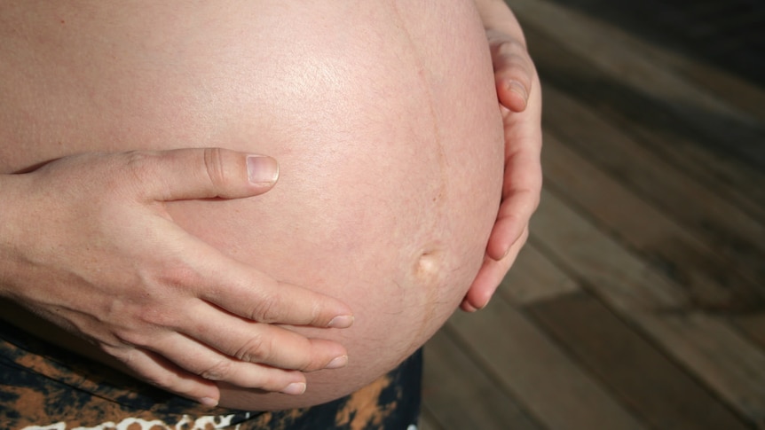 A woman holding her pregnant belly.