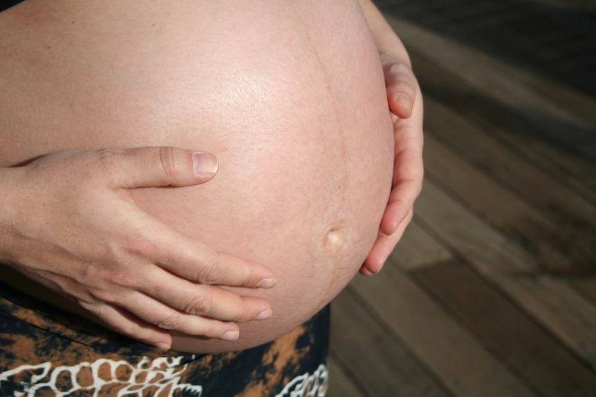 A woman holding her pregnant belly.