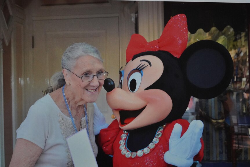 An elderly woman next to Minnie Mouse